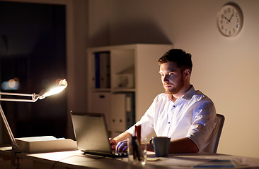 Image showing businessman typing on laptop at night office