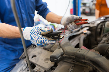 Image showing auto mechanic man with cleats charging battery