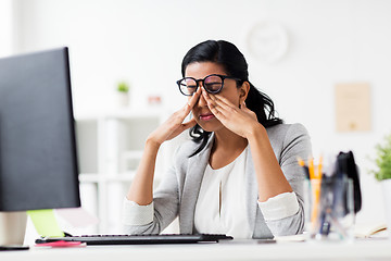 Image showing businesswoman rubbing tired eyes at office