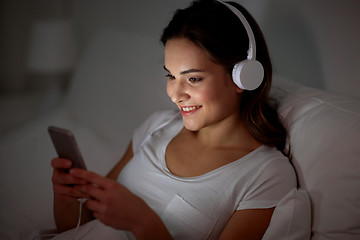 Image showing woman with smartphone and headphones in bed