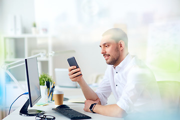 Image showing businessman with smartphone and computer at office