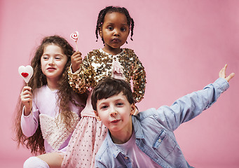 Image showing lifestyle people concept: diverse nation children playing together, caucasian boy with african little girl holding candy happy smiling 