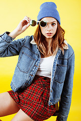 Image showing young pretty teenage woman emotional posing on yellow background, fashion lifestyle people concept