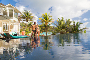 Image showing Couple relaxing by luxury hotel swimming pool.