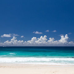 Image showing Tropical beach with white sand, emerald water, blue sky with clouds.