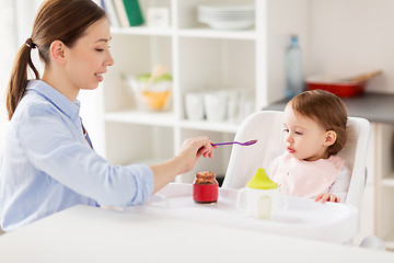 Image showing happy mother feeding baby with puree at home