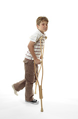 Image showing Wincing injured boy using crutches