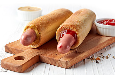 Image showing Two hotdogs on wooden cutting board