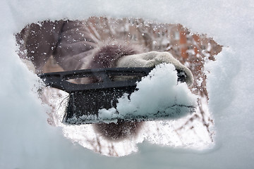 Image showing hand with brush cleaning window of car from the snow, closeup