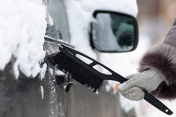 Image showing hand cleaning a car from the snow with a brush, closeup