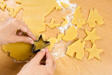 Image showing hands making christmas cookies with metal cutter