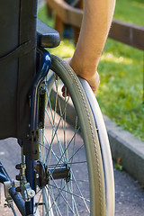 Image showing hand of young man on the wheel of wheelchair 