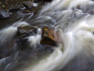 Image showing Strong current in river passing around rocks with long exposure