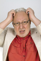 Image showing White haired senior with glasses tearing his hair