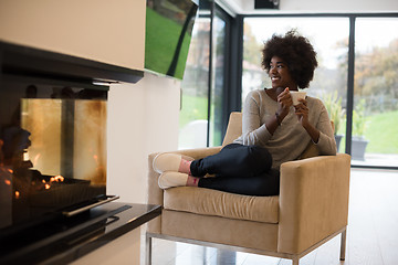 Image showing black woman drinking coffee in front of fireplace