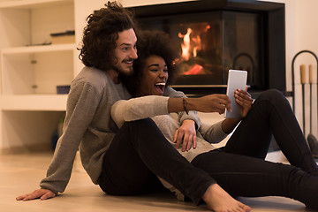 Image showing multiethnic couple using tablet computer on the floor