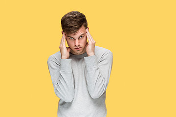 Image showing Tired businessman or The serious young man over yellow studio background with headache emotions