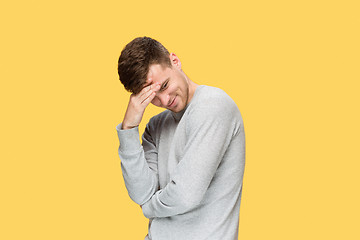 Image showing Tired businessman or The serious young man over yellow studio background with headache emotions