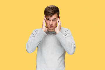 Image showing Tired businessman or The serious young man over yellow studio background with headache emotions