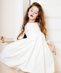 Image showing little cute girl at home, opening door well-dressed in white dre