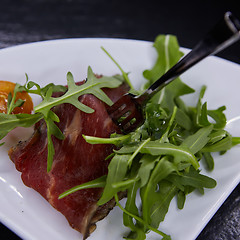 Image showing slice of prosciutto or jamon with arugula leafs