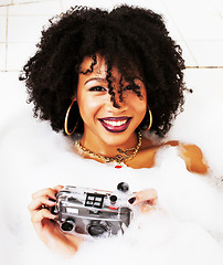 Image showing young afro-american teen girl laying in bath with foam, wearing 