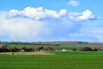 Image showing Rural landscape with a green field, clouds and farm