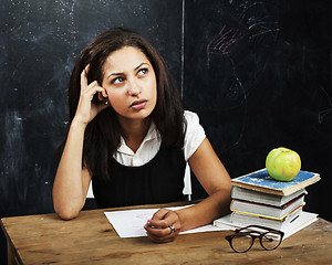 Image showing young cute teenage girl in classroom at blackboard seating on ta