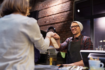 Image showing woman taking paper bag from seller at cafe