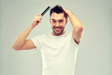 Image showing happy man brushing hair with comb over gray