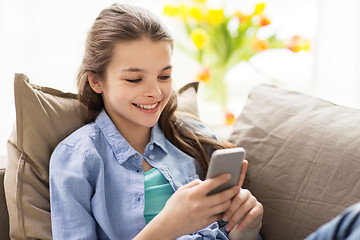 Image showing smiling girl texting on smartphone at home