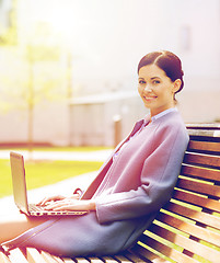 Image showing smiling business woman with laptop in city