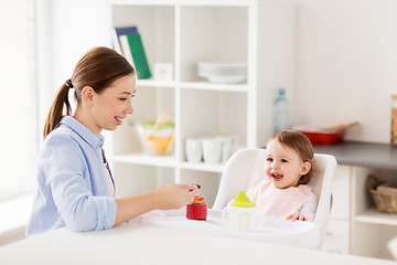 Image showing happy mother feeding baby with puree at home