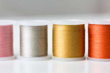 Image showing row of colorful thread spools on table