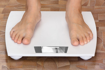 Image showing pair of female feet standing on the scale