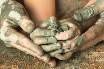 Image showing hands of adult helping child to work with raw clay