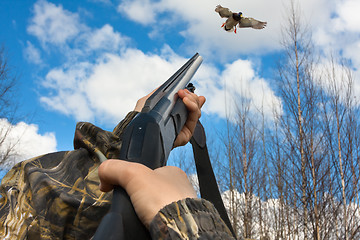 Image showing hands of hunter shooting from a shotgun to duck