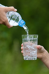 Image showing hand pouring water from bottle into glass