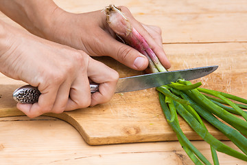 Image showing hands chopping green onion on the wooden cutting board