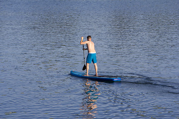 Image showing Man on Paddle Board paddling out to lake