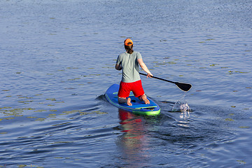 Image showing Man on Paddle Board paddling out to lake