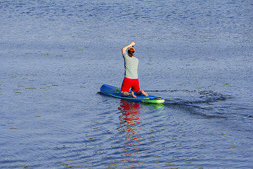 Image showing Man on Paddle Board paddling out to lake