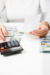 Image showing savings, finances, economy and home concept - close up of hands with calculator counting money and making notes at home