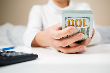 Image showing Close up of woman with calculator counting money