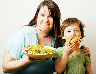 Image showing mature woman holding salad and little cute boy with hamburger te