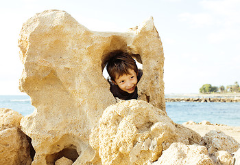 Image showing little cute boy on sea coast thumbs up playing with rocks