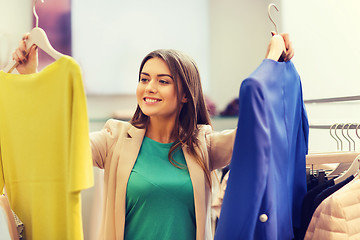 Image showing happy young woman choosing clothes in mall