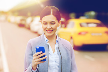 Image showing smiling woman with smartphone over taxi in city