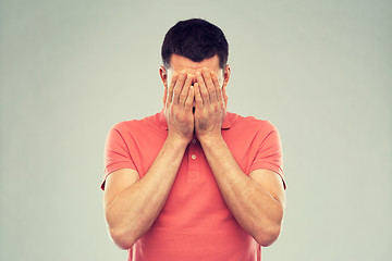 Image showing man in t-shirt covering his face with hands