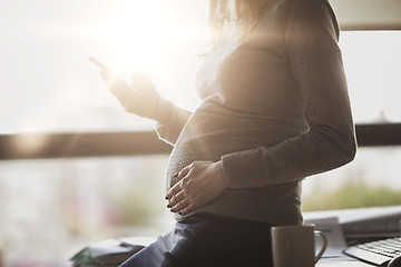 Image showing pregnant businesswoman with smartphone at office